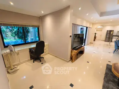 Spacious open-plan living area with modern decor and garden view, featuring a study nook and elegant furnishings.