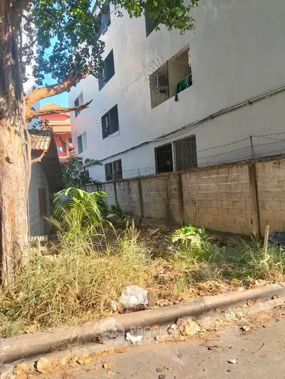 Urban residential building exterior with garden area and boundary wall.