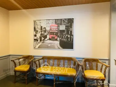 Charming seating area with yellow-cushioned chairs and a vintage London bus artwork, perfect for cozy gatherings.