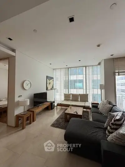 Spacious modern living room with large windows and stylish furniture in a high-rise apartment.
