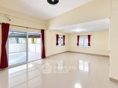 Spacious living room with large windows and sliding doors to balcony, featuring elegant red curtains.