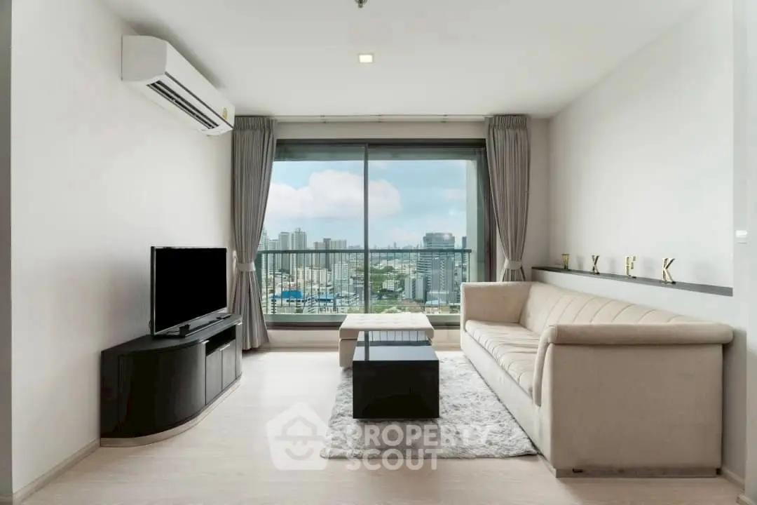 Modern living room with city view, featuring sleek furniture and large window.