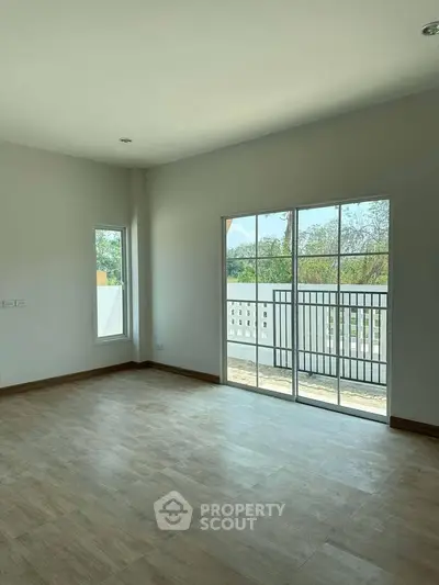 Spacious empty room with large windows and wooden flooring, ideal for customization.