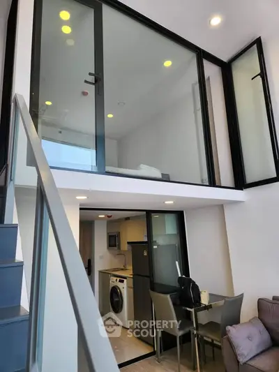 Modern duplex apartment with glass-walled mezzanine and sleek kitchen