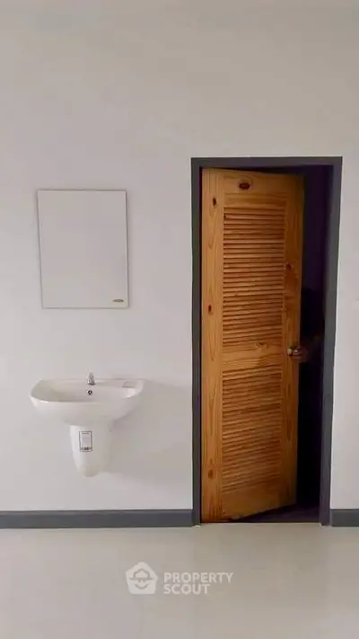 Minimalist bathroom with wooden door and wall-mounted sink