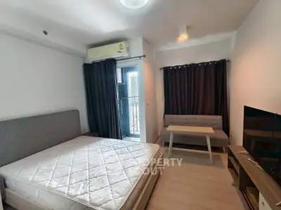 Modern studio apartment with bed, sofa, and TV, featuring natural light and minimalist decor.