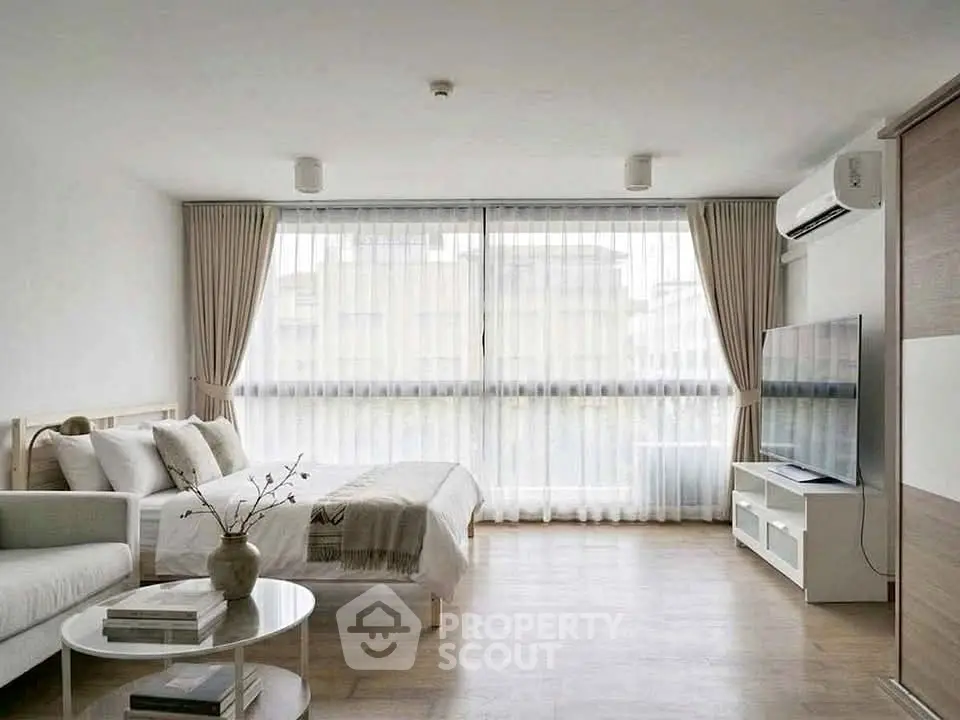 Modern living room with large windows, cozy sofa, and sleek TV setup.