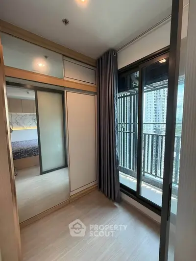 Modern bedroom with large window and balcony access in a high-rise apartment.