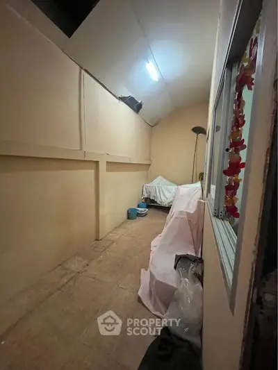Spacious storage room with high ceiling and tiled floor, ideal for versatile use.