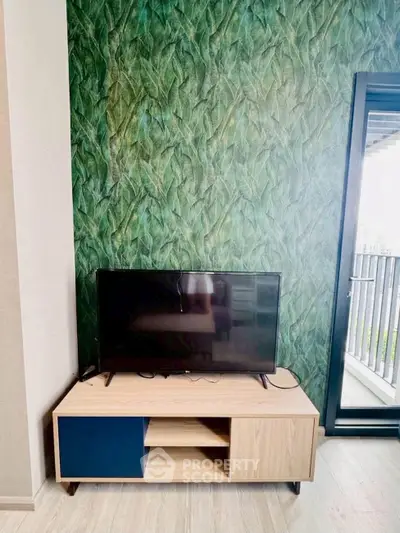 Modern living room with stylish TV stand and leafy wallpaper, featuring a balcony view.