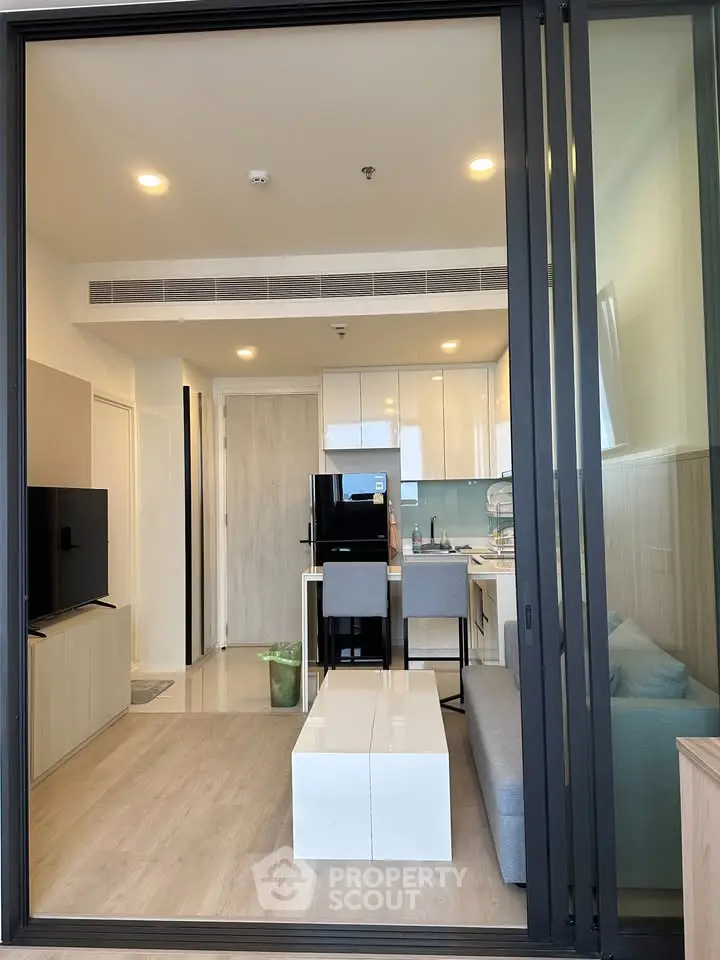 Modern open-plan living room with sleek kitchen and stylish decor in a contemporary apartment.