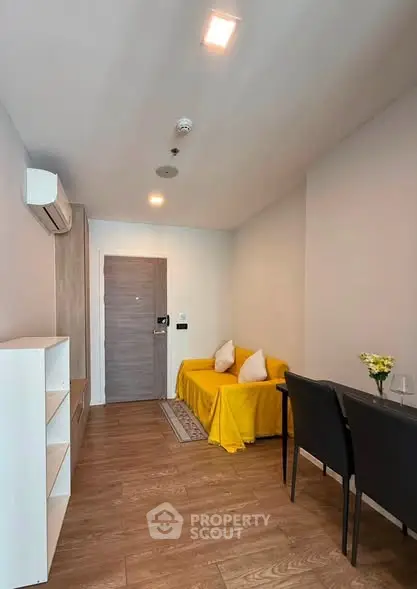 Modern living room with wooden flooring, yellow sofa, and dining area in a cozy apartment.