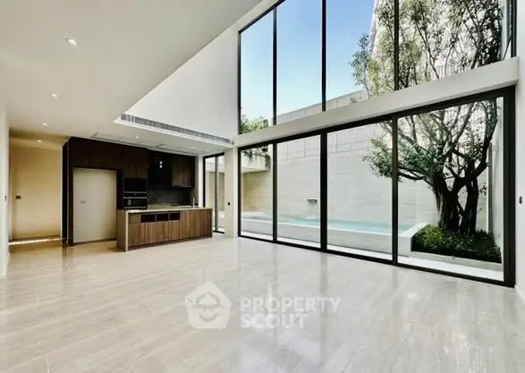 Spacious modern living room with floor-to-ceiling windows and pool view