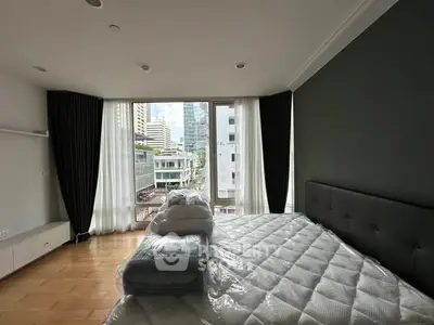 Spacious bedroom with city view and modern decor in high-rise apartment.