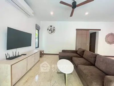 Spacious living room with modern brown sofa, flat-screen TV, and ceiling fan in a stylish home.