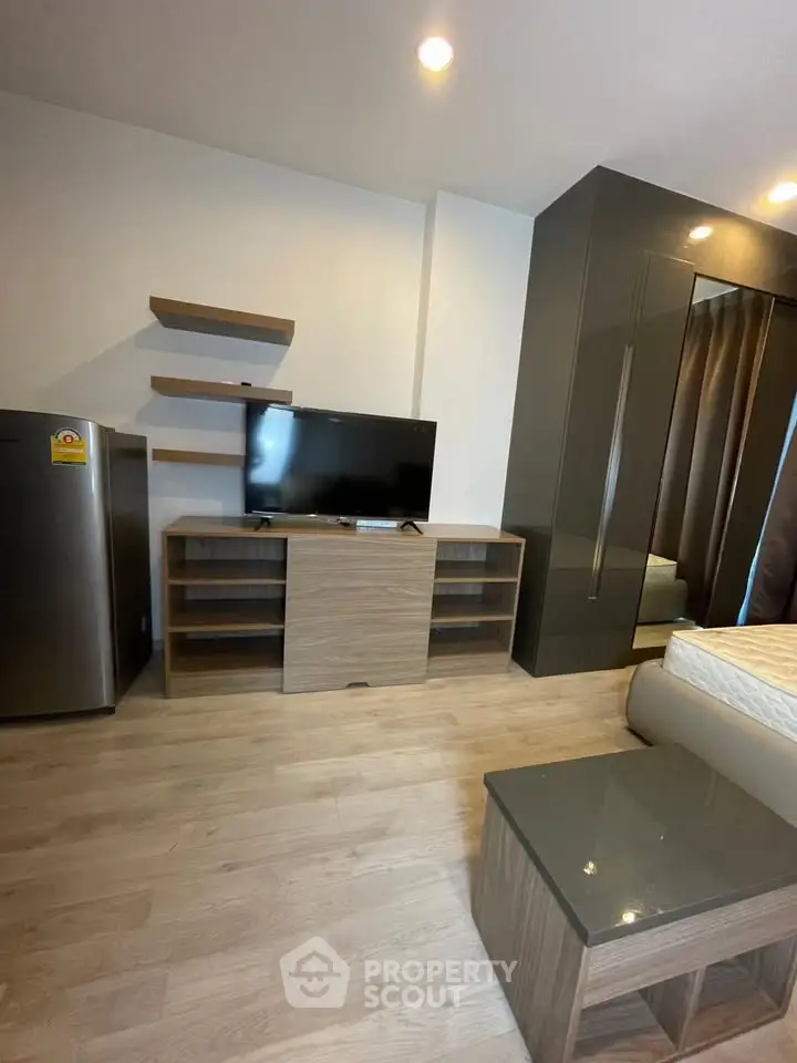 Modern bedroom with sleek furniture and flat-screen TV, perfect for urban living.