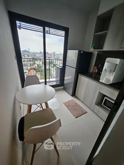 Modern kitchen with balcony view, sleek appliances, and cozy dining area in urban apartment.