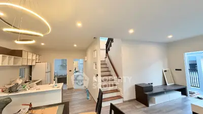 Modern open-plan living area with stylish lighting and staircase, perfect for contemporary living.