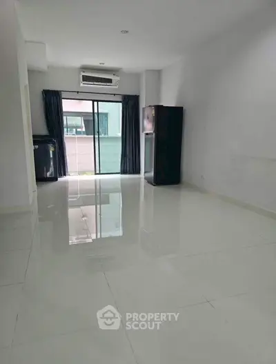 Spacious unfurnished living room with glossy tiled floors and large window for natural light.