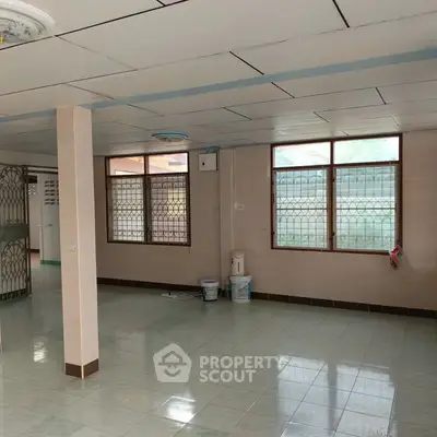Spacious interior with tiled flooring and large windows, ideal for versatile living space.