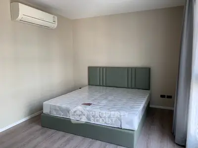 Spacious bedroom with modern air conditioning and natural light, featuring a stylish bed frame and minimalist decor.