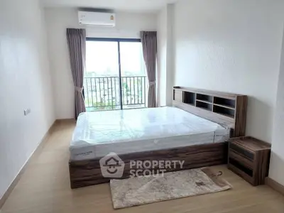 Spacious bedroom with large window and modern wooden furniture in a bright apartment.