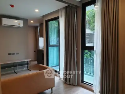 Modern living room with large windows and air conditioning, overlooking a lush garden.