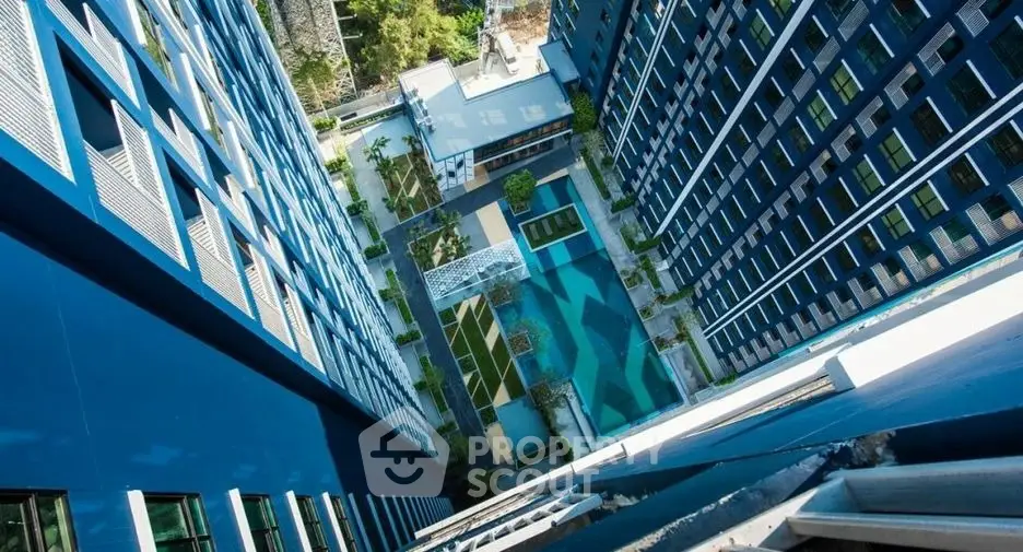 Stunning aerial view of modern high-rise building with central courtyard and pool.