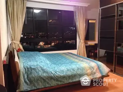 Cozy bedroom with city view and elegant decor, featuring large windows and stylish furnishings.