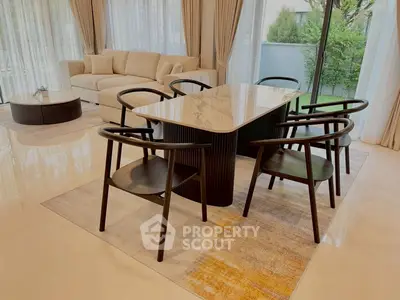 Elegant living room with modern dining set and large windows overlooking garden
