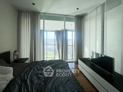 Modern bedroom with large windows offering stunning city views, sleek furniture, and elegant decor.