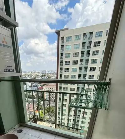 High-rise apartment balcony with city view and clothes drying rack.
