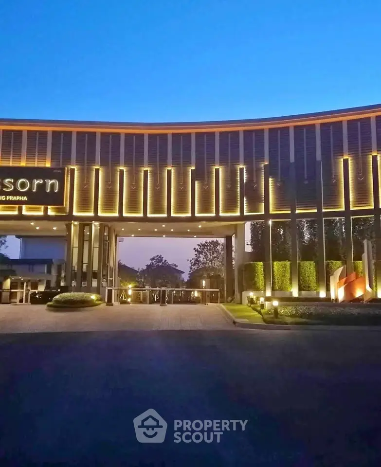 Stunning modern building entrance with elegant lighting and lush landscaping at dusk.