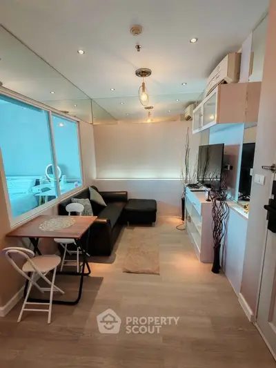 Modern living room with cozy seating and stylish decor in a compact apartment.