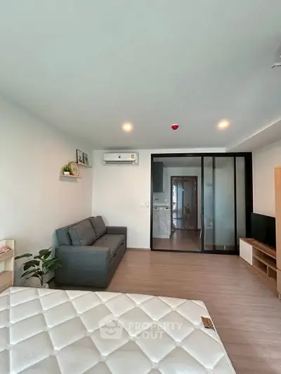 Modern living room with sleek design, featuring a cozy sofa, wall-mounted air conditioner, and sliding glass doors.