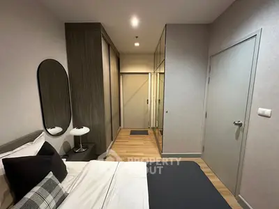 Modern bedroom with sleek design, mirrored closet doors, and cozy bedding in a stylish apartment.
