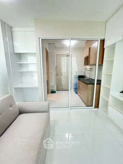 Modern living room with sleek kitchen view, featuring elegant white and wood cabinetry.