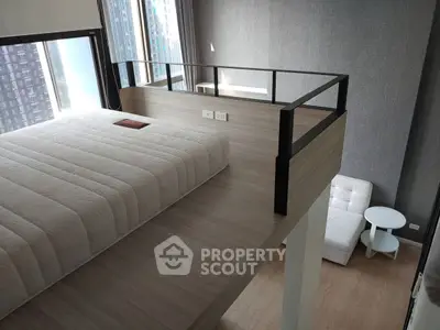 Modern loft bedroom with elevated bed and cozy seating area, featuring sleek design and natural light.