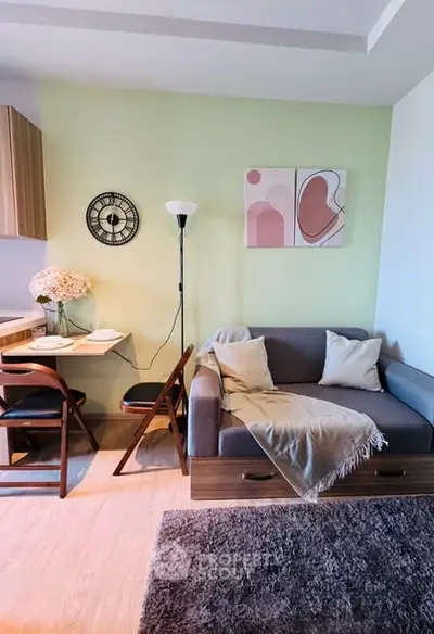 Cozy living room with modern decor, featuring a compact sofa, wall art, and a small dining area.