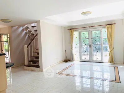 Spacious living room with large windows and elegant staircase