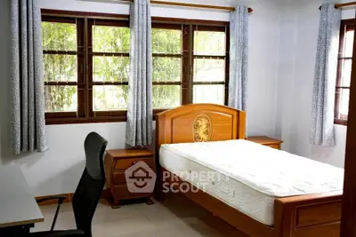 Cozy bedroom with wooden furniture and large windows for natural light.