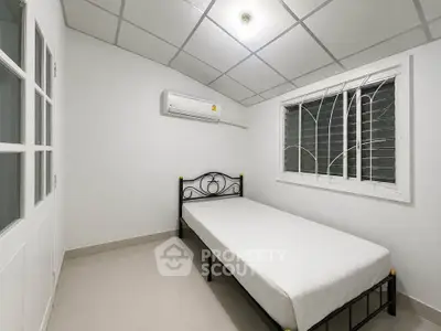 Cozy minimalist bedroom with single bed and air conditioning in modern apartment.