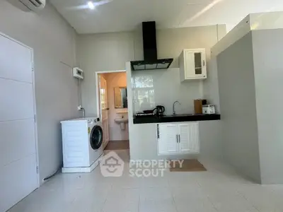 Modern kitchen with washing machine and sleek cabinetry in a bright, open space.
