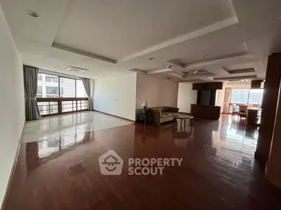 Spacious open-plan living room with wooden flooring and large windows