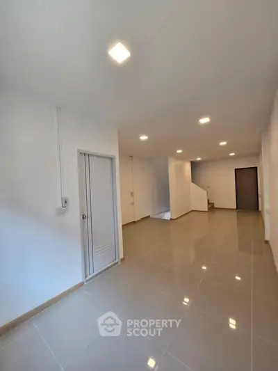 Spacious modern interior with sleek tile flooring and recessed lighting, ideal for versatile living space.