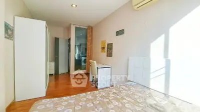 Bright bedroom with modern decor and wooden flooring, featuring a washing machine in the background.