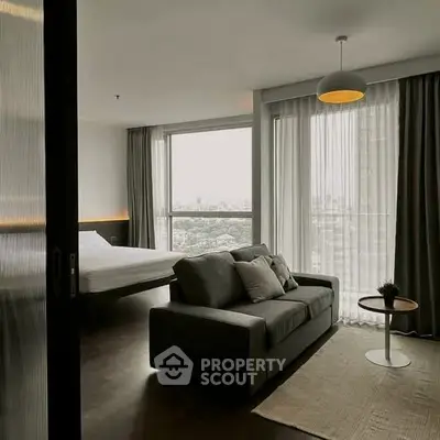 Modern living room with cozy sofa and city view from large windows in a stylish apartment.