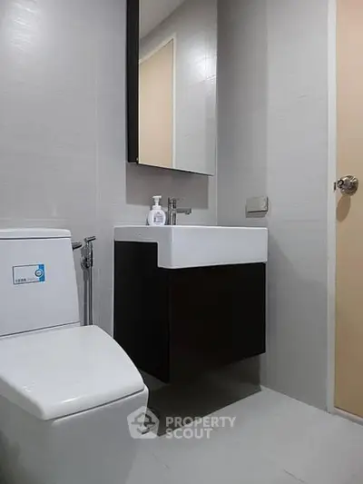 Modern bathroom with sleek fixtures and minimalist design, featuring a wall-mounted sink and toilet.