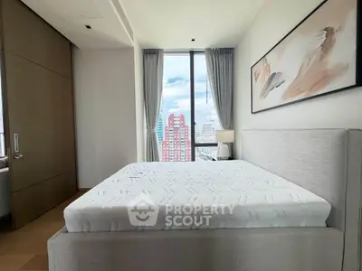 Spacious bedroom with large window offering stunning city view, modern decor, and elegant furnishings.