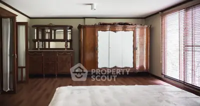 Elegant bedroom with vintage wooden furniture and large windows for natural light.